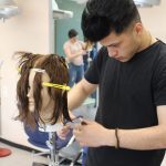 Schüler schneidet Haare einer Friseur-Puppe