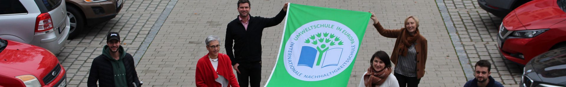 Lehrer mit Umweltschulen Logo als Fahne